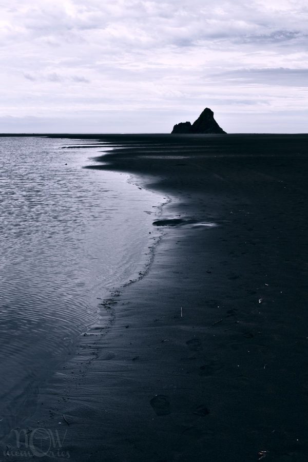 Karekare black sand beach rock coast sea in a cloudy day